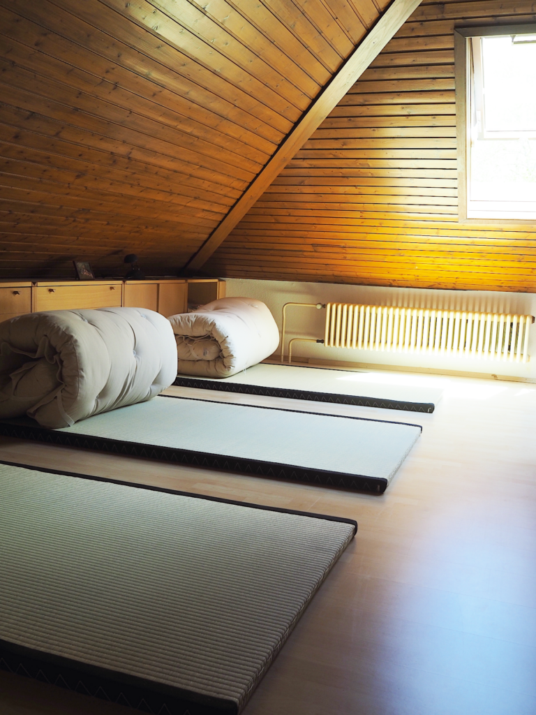 Ein Zimmer mit drei Futons auf Tatami-Matten.